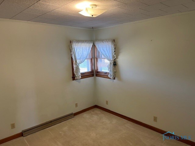 unfurnished room featuring ornamental molding, carpet floors, and a baseboard radiator