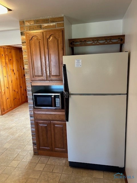 kitchen featuring wooden walls and white fridge