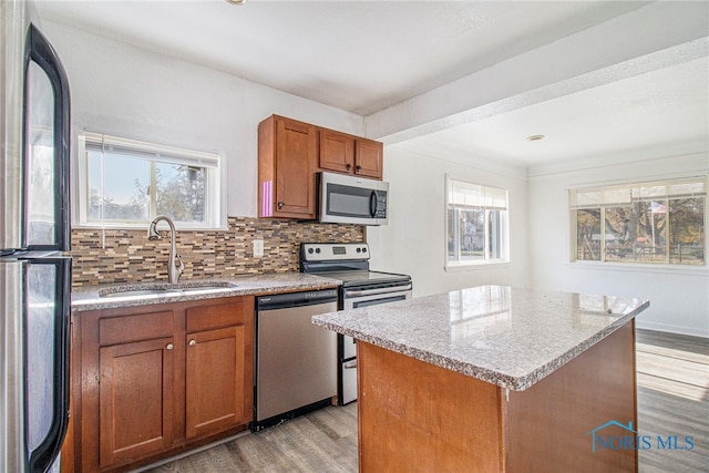 kitchen featuring a kitchen island, decorative backsplash, light hardwood / wood-style flooring, stainless steel appliances, and sink