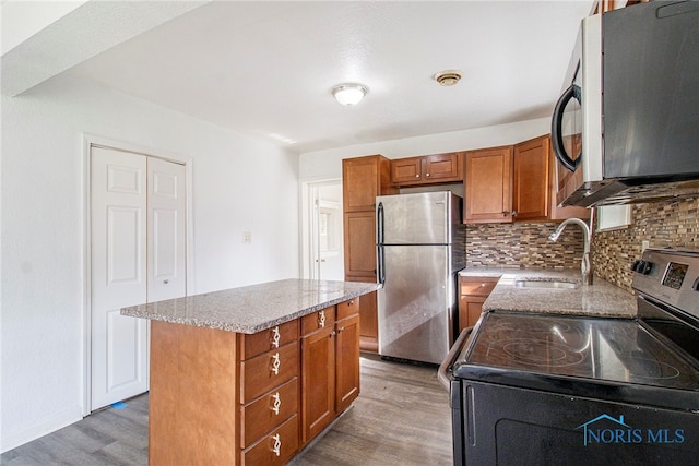 kitchen with hardwood / wood-style floors, sink, a center island, and appliances with stainless steel finishes