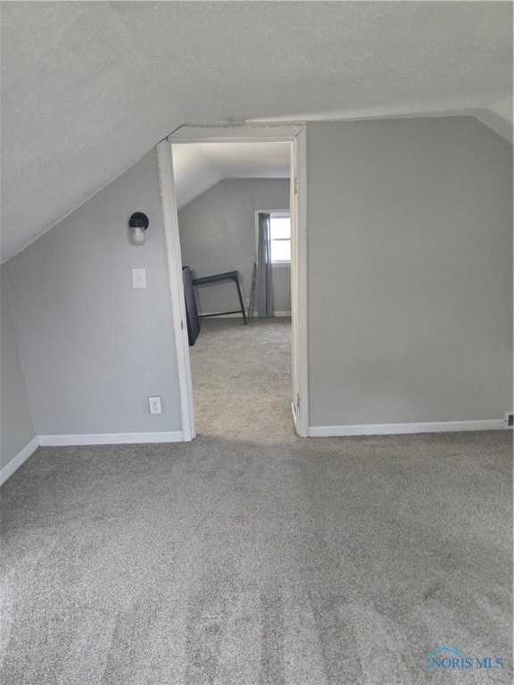 bonus room featuring vaulted ceiling, light carpet, and a textured ceiling