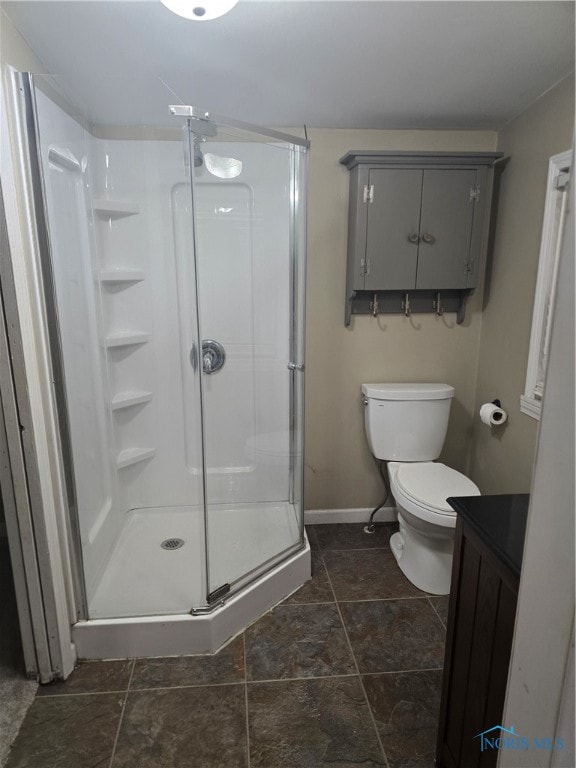 bathroom featuring a shower with door, toilet, and vanity