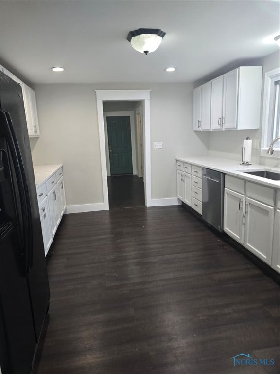 kitchen featuring dishwasher, dark hardwood / wood-style floors, black fridge, sink, and white cabinets