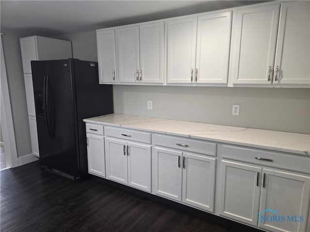 kitchen with black fridge with ice dispenser, white cabinetry, light stone counters, and dark hardwood / wood-style flooring