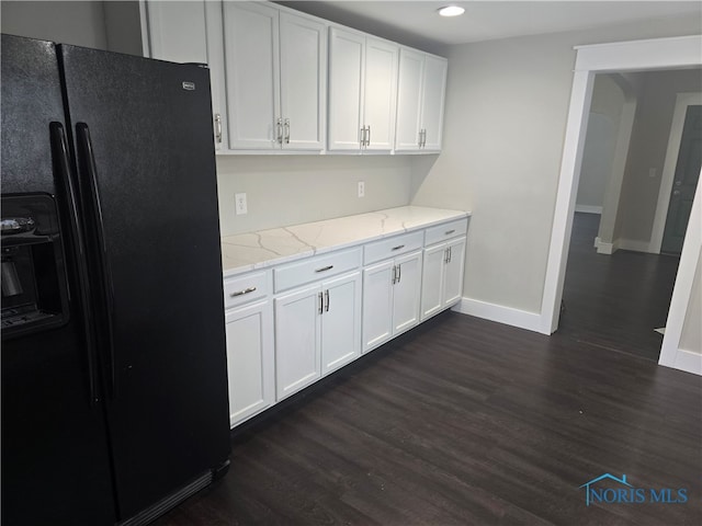 kitchen featuring dark hardwood / wood-style flooring, white cabinetry, light stone countertops, and black fridge