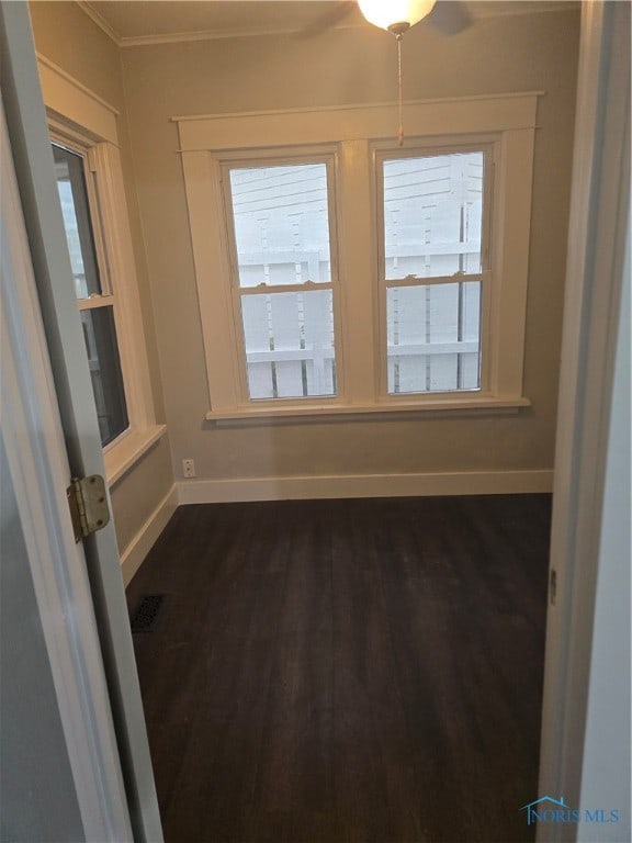 empty room with crown molding, dark hardwood / wood-style floors, and ceiling fan