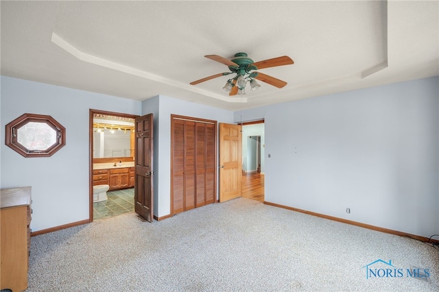 unfurnished bedroom featuring light carpet, a closet, a raised ceiling, and ceiling fan