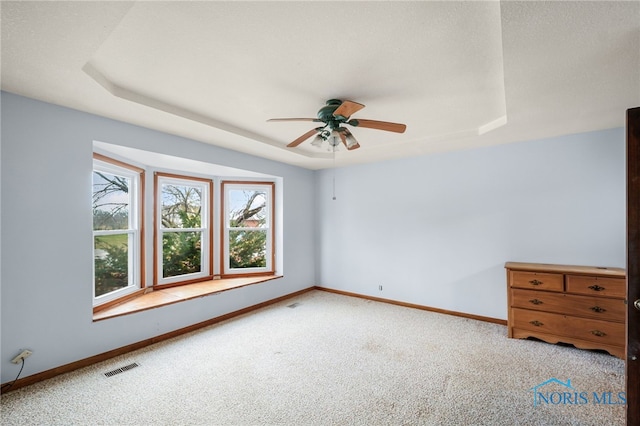 unfurnished room featuring light carpet, a raised ceiling, and ceiling fan