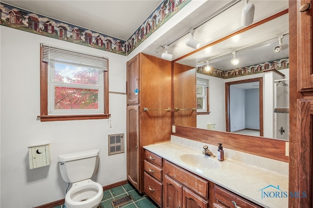 bathroom with toilet, vanity, heating unit, and rail lighting