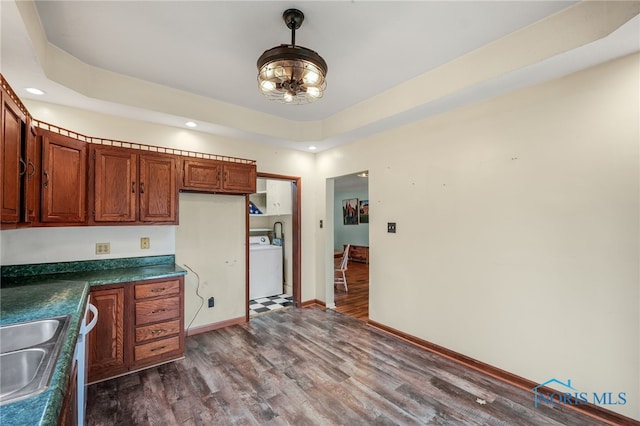 kitchen with washer / dryer, sink, and dark hardwood / wood-style floors