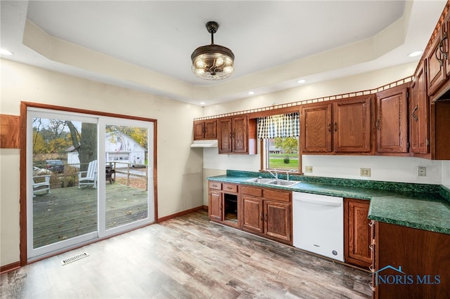 kitchen with light wood-type flooring, a raised ceiling, dishwasher, and a wealth of natural light