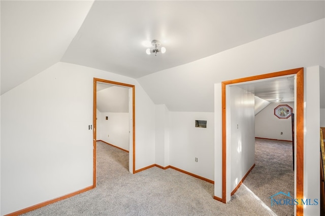 bonus room with vaulted ceiling and light colored carpet