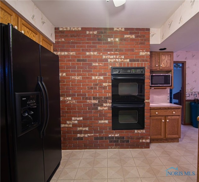 kitchen featuring black appliances and brick wall