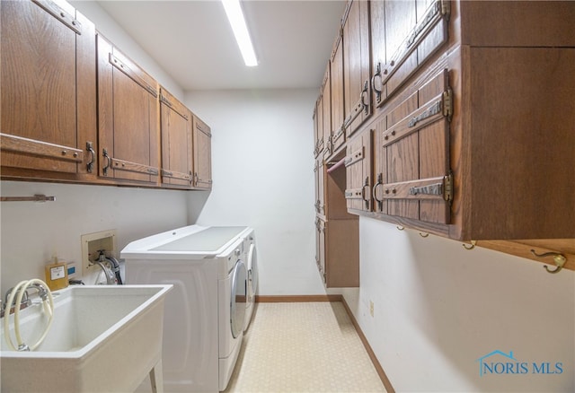 clothes washing area with washer and clothes dryer, cabinets, and sink