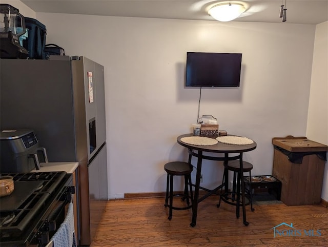 kitchen with black range with electric cooktop, stainless steel refrigerator with ice dispenser, and hardwood / wood-style floors