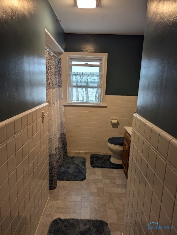 bathroom featuring a shower with shower curtain, vanity, toilet, and tile walls