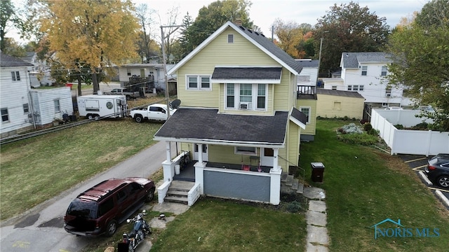 rear view of house featuring covered porch and a lawn