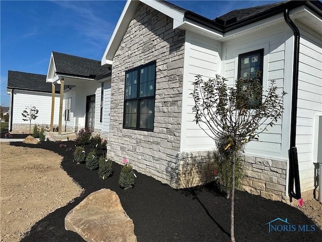 3640 Turtle Creek Dr, Perrysburg, OH 43551 - view of side of home featuring stone siding and roof with shingles