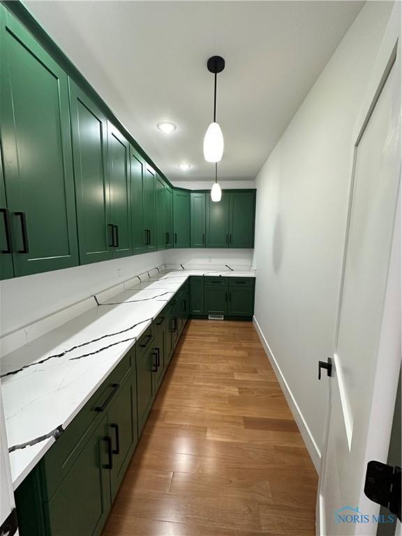 3640 Turtle Creek Dr, Perrysburg, OH 43551 - kitchen featuring green cabinets, light wood-style flooring, decorative light fixtures, baseboards, and light stone counters