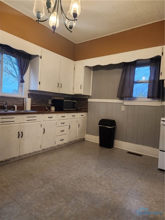 kitchen with white cabinetry, sink, decorative light fixtures, and decorative backsplash