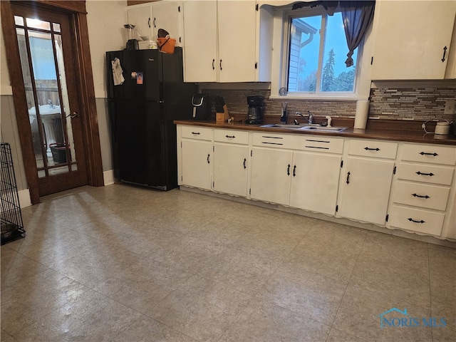 kitchen featuring black refrigerator, plenty of natural light, sink, and tasteful backsplash