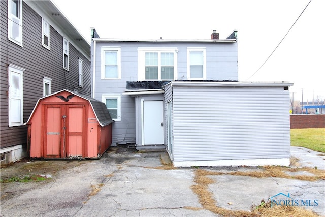 rear view of property featuring a storage shed