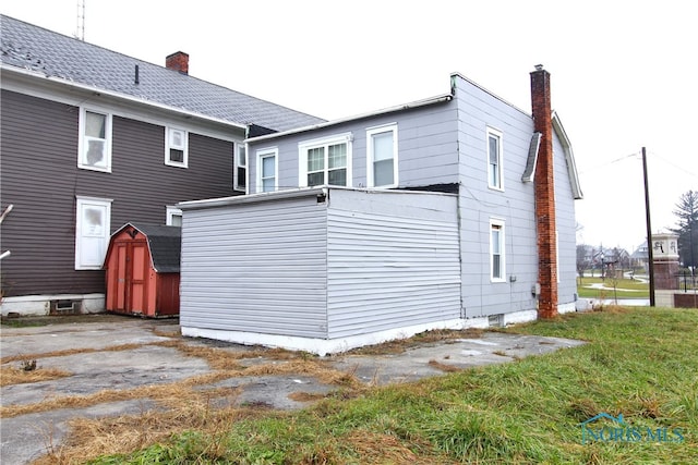 back of house with a storage unit