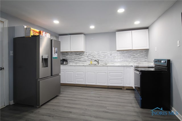 kitchen featuring white cabinets, stainless steel refrigerator with ice dispenser, sink, and black electric range oven