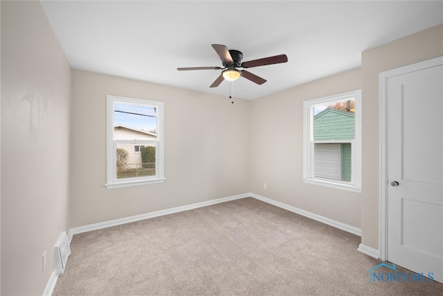 spare room with ceiling fan and light carpet