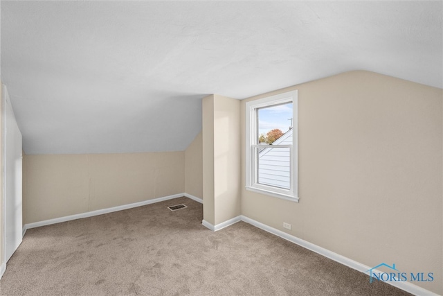 additional living space featuring lofted ceiling and light carpet