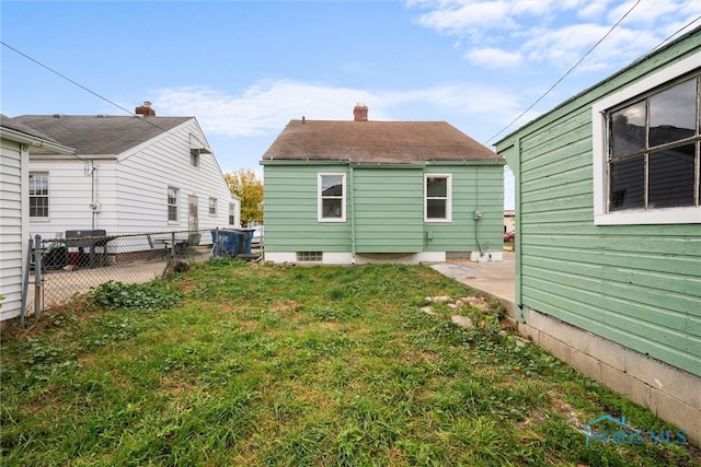 back of house with a patio and a lawn