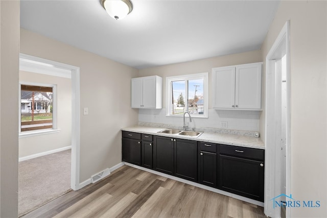 kitchen featuring white cabinetry, light wood-type flooring, and sink