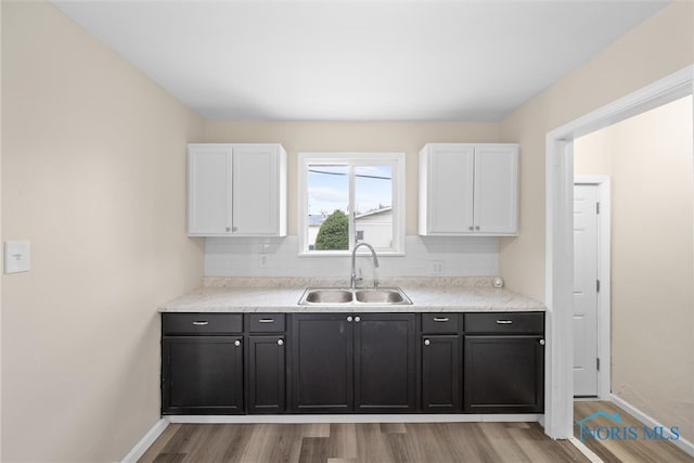 kitchen with white cabinetry, light hardwood / wood-style flooring, and sink