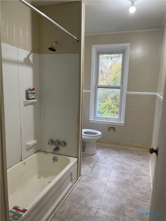 bathroom with  shower combination, tile patterned floors, toilet, ornamental molding, and tile walls