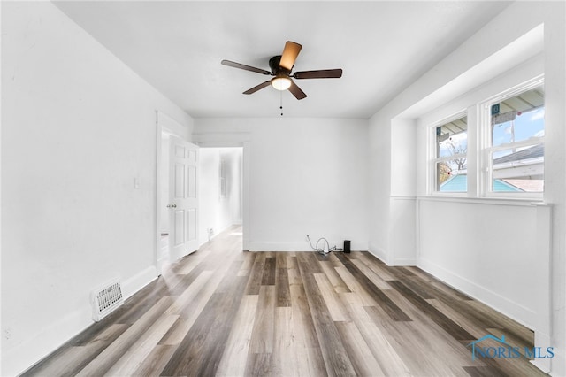 empty room with ceiling fan and dark hardwood / wood-style flooring