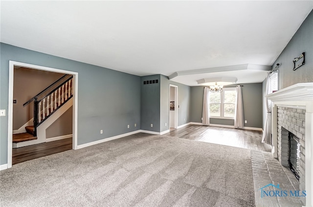 unfurnished living room featuring a fireplace, an inviting chandelier, and light hardwood / wood-style flooring