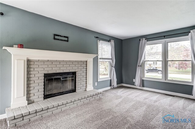 unfurnished living room featuring carpet flooring and a brick fireplace