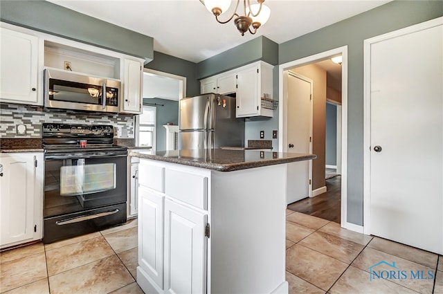 kitchen featuring white cabinets, decorative backsplash, appliances with stainless steel finishes, and a center island