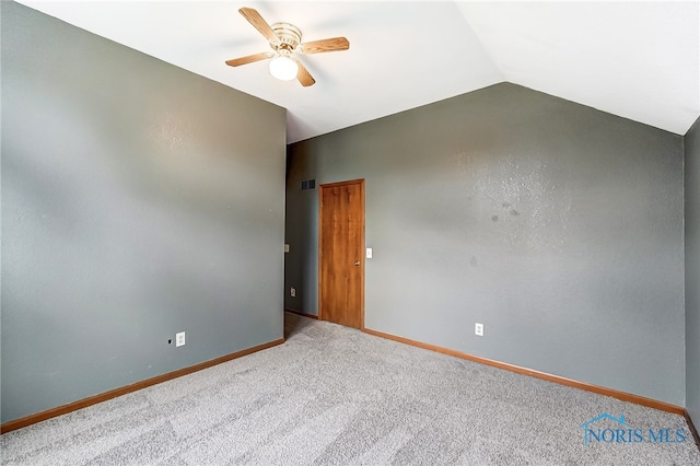 empty room featuring ceiling fan, vaulted ceiling, and carpet