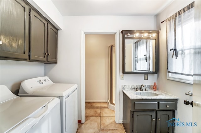 laundry area featuring washing machine and dryer, cabinets, sink, and light tile patterned floors