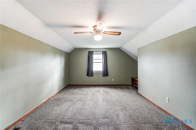 additional living space featuring vaulted ceiling, carpet flooring, ceiling fan, and a textured ceiling