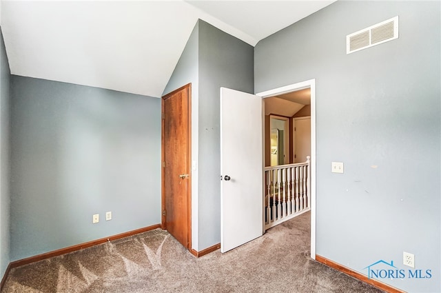 unfurnished bedroom with light colored carpet and lofted ceiling