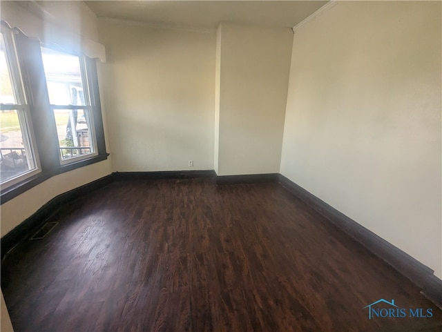 empty room featuring dark wood-type flooring and ornamental molding