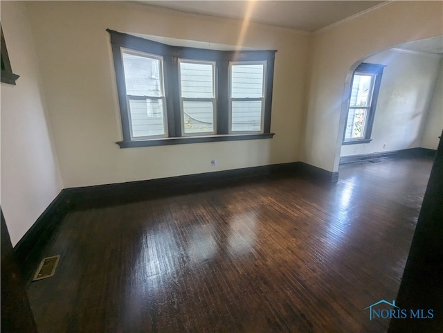 unfurnished room with ornamental molding, plenty of natural light, and dark hardwood / wood-style floors