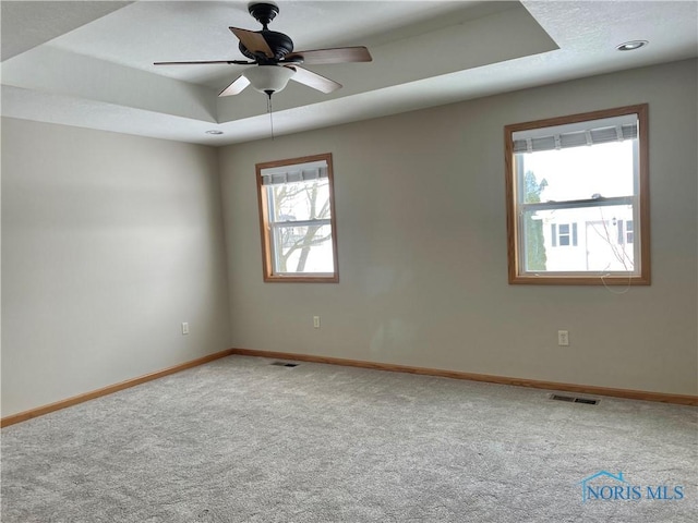 unfurnished room featuring ceiling fan, a tray ceiling, and carpet flooring