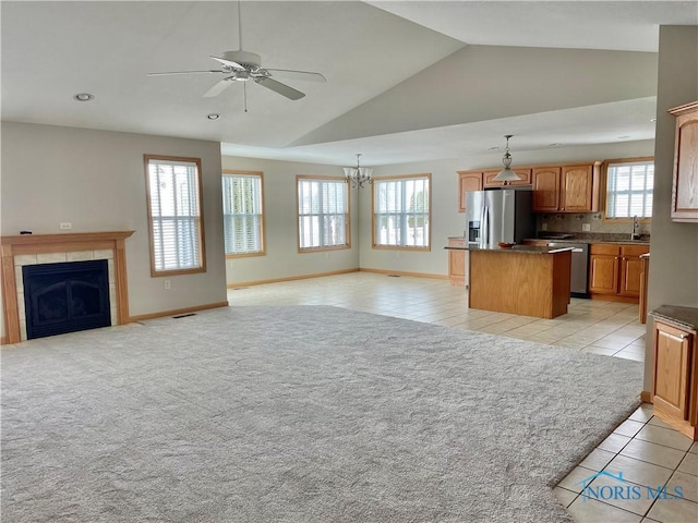 kitchen featuring stainless steel appliances, a tiled fireplace, decorative light fixtures, light tile patterned flooring, and a kitchen island