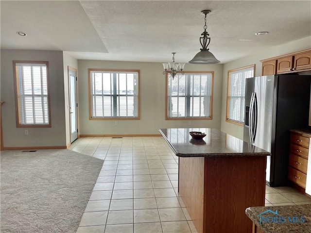 kitchen featuring a kitchen island, decorative light fixtures, an inviting chandelier, stainless steel fridge, and light tile patterned floors