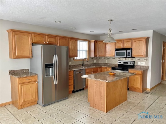 kitchen featuring appliances with stainless steel finishes, backsplash, a kitchen island, pendant lighting, and sink