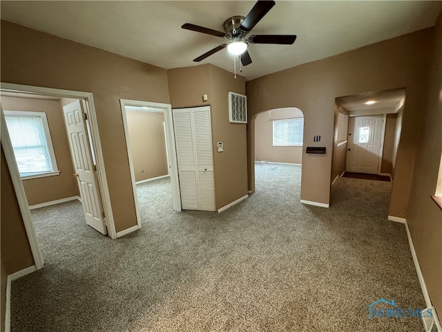 unfurnished bedroom with multiple windows, carpet flooring, and ceiling fan