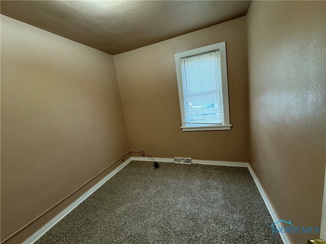 carpeted empty room featuring a textured ceiling